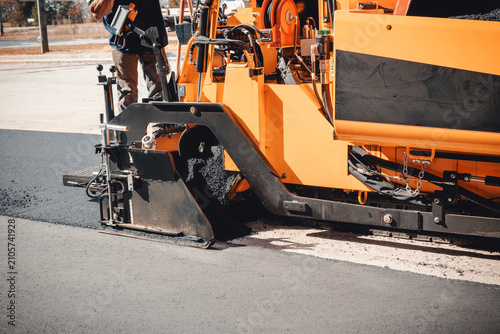Φωτογραφία Asphalt paving large machine is laying fresh asphalt on road while workers overs