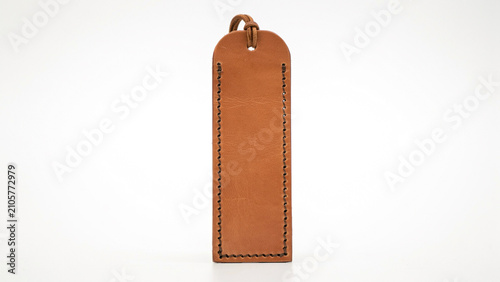 Minimalist tan leather bookmark with a rounded and a simple loop of dark brown leather cord against white