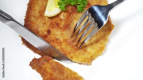 Wiener Schnitzel schneiden mit Gabel und Messer auf weißem Hintergrund 