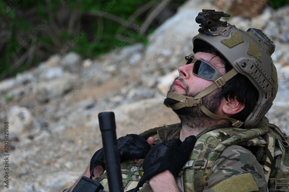 Obraz premium Focused military infantry soldier lying prone on rugged rocky terrain aiming a tactical assault rifle during a dangerous combat training mission for national defense and special security.