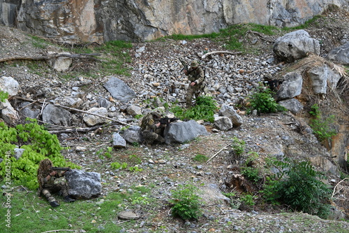 Принти на полотні Military team in camouflage takes dispersed ambush positions in rocky terrain during a tactical field exercise