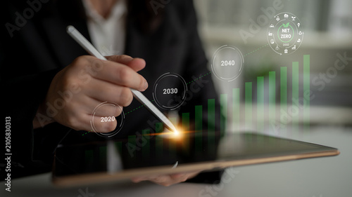 Foto A business professional uses a stylus on a tablet, analyzing growth projections for achieving sustainability and net zero emissions by 2040, symbolizing strategic planning