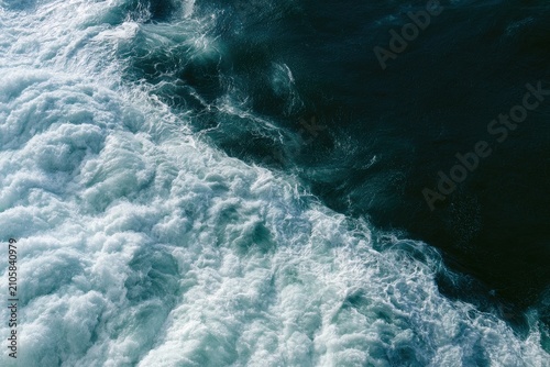 Turbulent, foamy white water meets deep, dark ocean depths