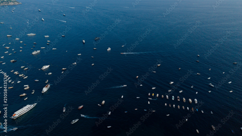 Obraz premium Boats and yachts scattered across the vast dark blue mediterranean sea near the amalfi coast, italy, captured from an aerial perspective during summer