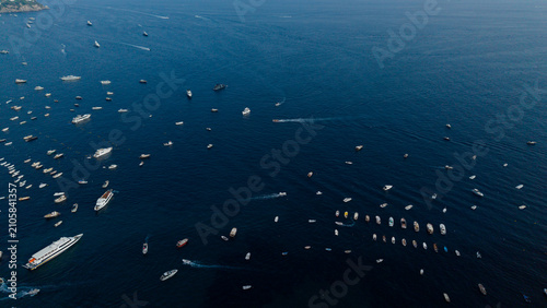 Boats and yachts scattered across the vast dark blue mediterranean sea near the amalfi coast, italy, captured from an aerial perspective during summer