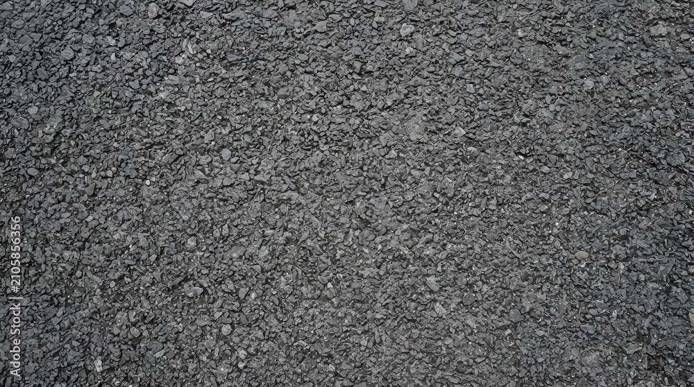 Fototapeta premium Rough asphalt road surface texture with dark grey gravel and small stones creating a coarse and gritty pattern for urban infrastructure