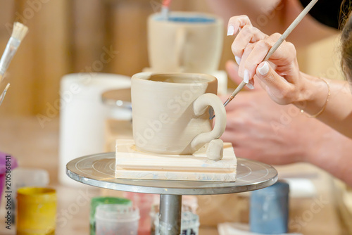 Foto A woman steadily glazes a white ceramic mug on a rotating tray in a pottery stud