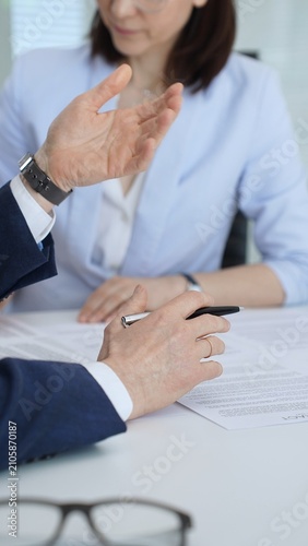 Businessmen and woman negotiating terms of a contract, discussing agreement details on paperwork, preparing to sign legal documents to finalize a professional deal