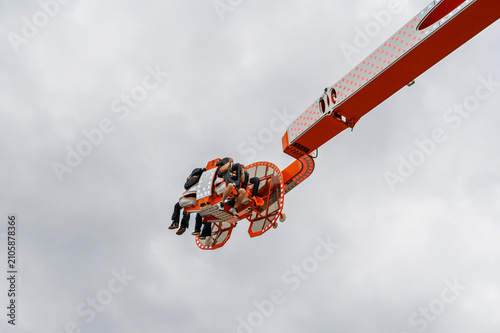Canvas Print People enjoying a thrilling amusement park ride against a cloudy sky