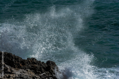 Fotografie Vague éclatant en embruns sur une côte rocheuse