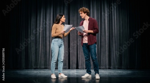 A man and woman review papers together during theater rehearsals on stage.