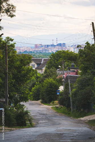 Suburban Street on Hill Overlooking City Skyscrapers and High Rises in Distance
