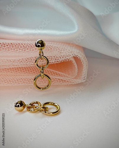 Schilderij op canvas Gold dangle earrings with interlocking rings on white background