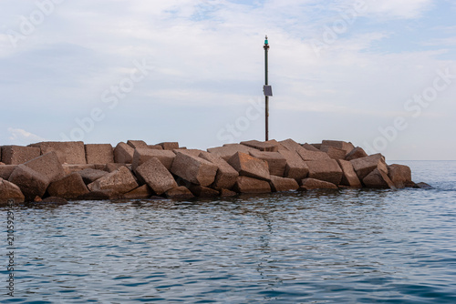 Konstfotografi Green navigation beacon on concrete breakwater blocks guarding calm sea waters a