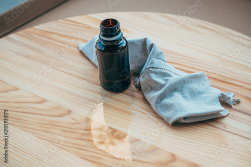 Bottle of wood treatment flax oil and soft cotton cloth ready for applying a protective finish to natural timber. Wood maintenance, restoration and craftsmanship theme.