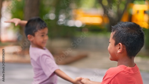 Cuadro en lienzo Little Asian children having fun playing games together outdoors in park