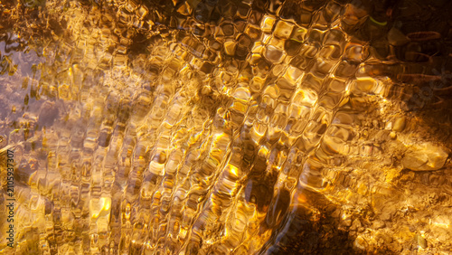 Принти на полотні Golden light refracting through shimmering water ripples and caustic patterns on