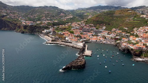 Madeira island, Camara de Lobos drone panoramic flight from right to left revealing the coastal village, scenic bay and colorful fishing boats, Portugal cinematic footage 4k