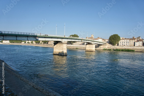 Принти на полотні Arles bridge spanning the rhone river with city buildings and a clear blue sky