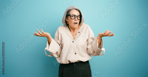 Fotografie Elder woman shrugging shoulders with hands open, showing confusion and doubt ove