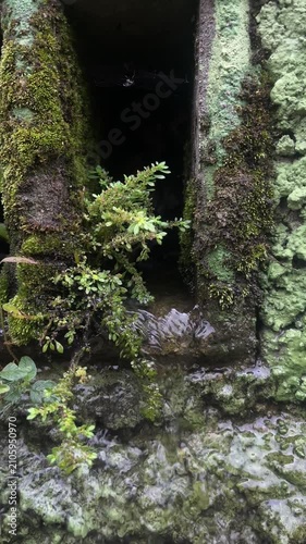Moss covered ancient ruins with water flowing through stone doorway