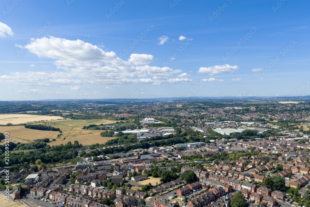 Fototapeta premium Aerial photo overlooking Mexborough in South Yorkshire England showing residential housing industrial estates farmland and surrounding countryside beneath a bright blue summer sky with scattered cloud