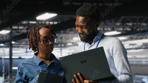 Schilderij op canvas Data center system administrators review AI and LLM visualizations on a laptop while IT specialists analyze neural network outputs and maintain stable equipment operations across the server hub