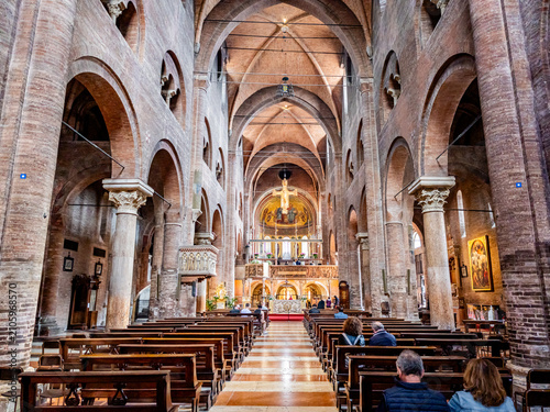 Visitors viewing the monumental nave and high altar of Modena Cathedral, a UNESCO World Heritage site displaying significant Romanesque architecture, arches, columns, and religious art