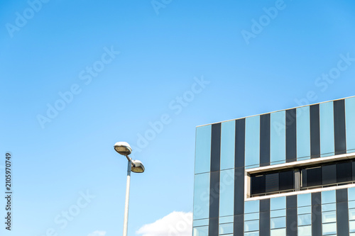 Modern glass office building with streetlight beneath a clear blue sky in a contemporary business district