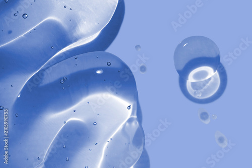 Cosmetic gel texture blue background with clear liquid serum sample and air bubbles close up macro