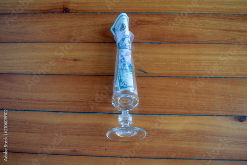фотографія US Dollar Bill Inside Glass Vase on Wooden Floor