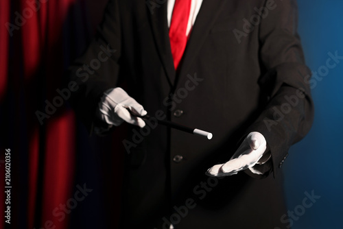 Foto Magician showing trick with wand on stage, closeup