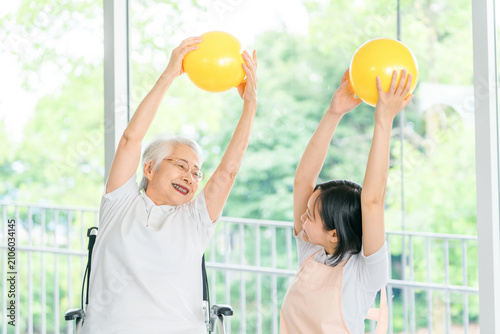 Foto Young caregivers, physical therapists, and care staff conduct ball exercises with a senior woman in a wheelchair to maintain her health