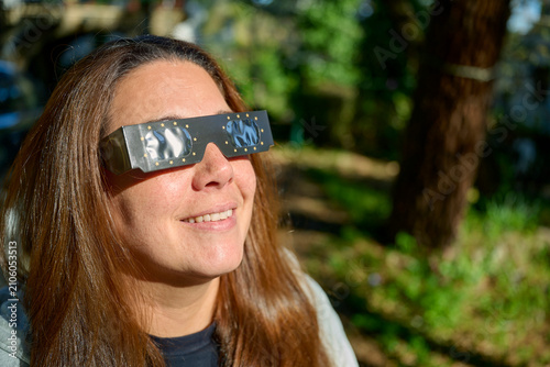Bild auf Leinwand Woman with Protective Solar Eclipse Goggles Looking at Sun at Sunset
