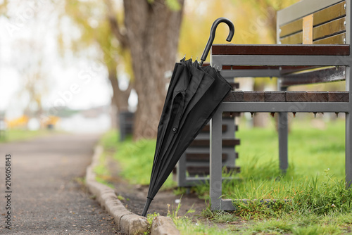 Black umbrella beside bench...