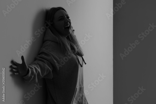 Angry mature woman screaming near wall in room. International Stress Awarenes...