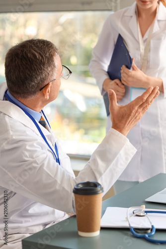 Mature doctor working with his assistant in medical office