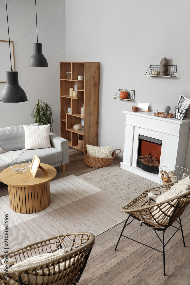 Obraz premium Interior of modern living room with fireplace, grey sofa and chairs