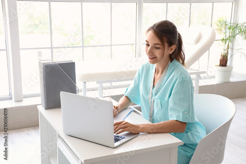 Female medical intern using laptop at hospital
