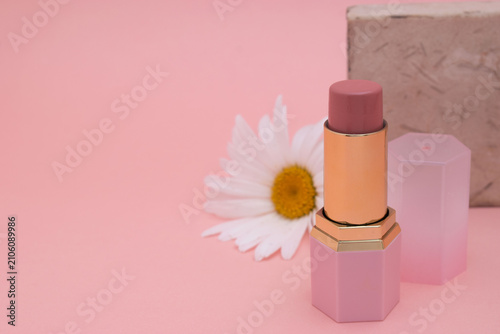Pink lipstick with daisy flower on pastel background