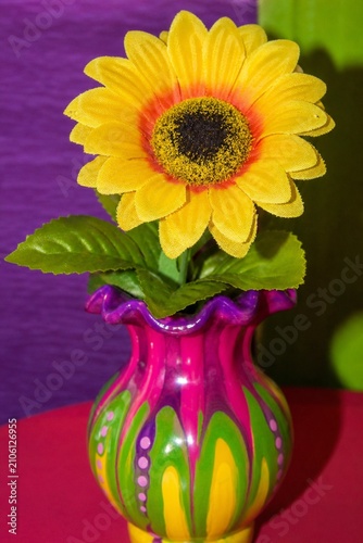 A cheap plastic flower in a garish vase, tacky aesthetic with bright colors.