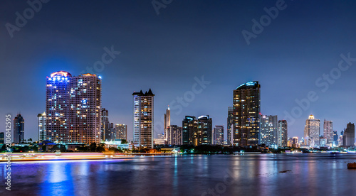 Obraz na plátne Panoramic Bangkok cityscape at night featuring illuminated skyscrapers beside Chao Phraya River