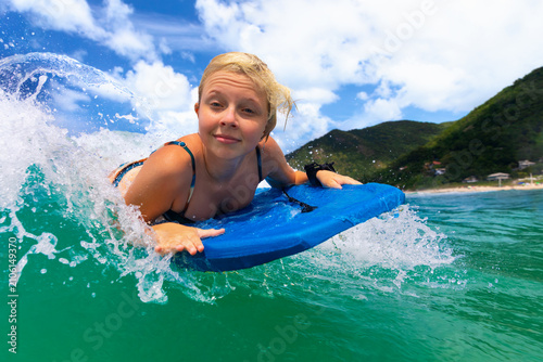 Foto Happy young surfer girl with bodyboard have fun on beach, riding on small ocean waves