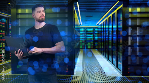 Plakat Data center. IT specialist monitors server infrastructure with a laptop, managing network operations, cybersecurity, system performance and cloud computing services.