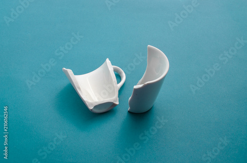 Photography Closeup of a broken cup on a blue surface, showing its fragility and imperfection