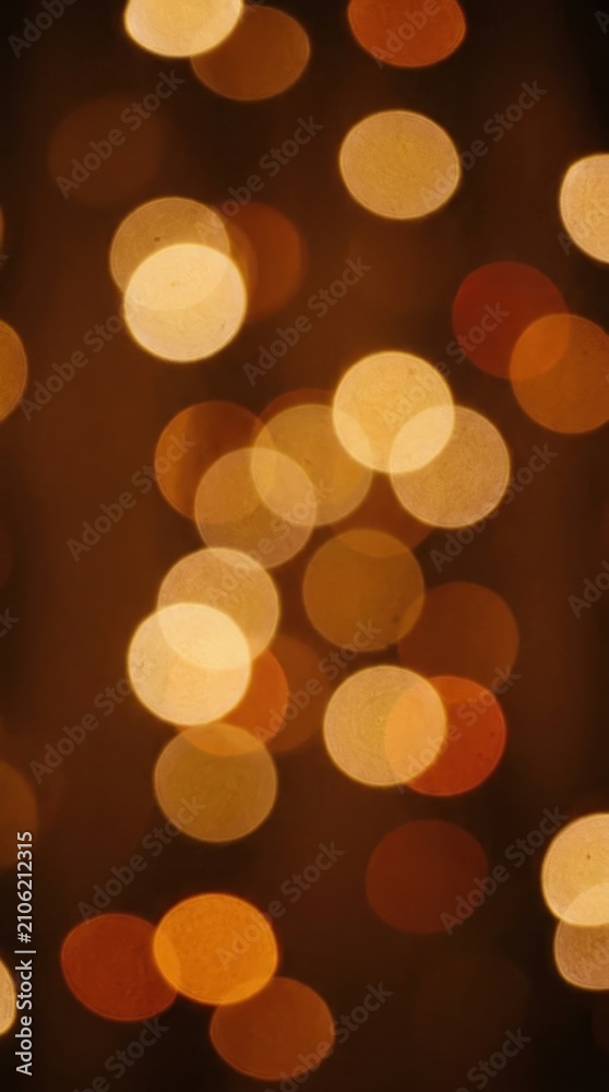 Fototapeta premium Abstract glowing bokeh light circles scattered on dark brown background