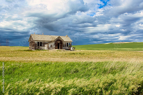 Abandoned Homestead Waiting for a Summer Thunderstorm on the Green Grass Prairie in Eastern Montana.