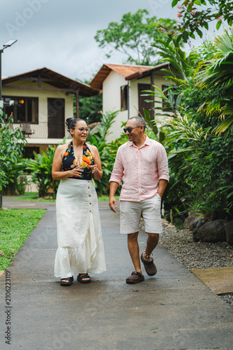 Obraz na plátně Smiling couple walking together on tropical resort path