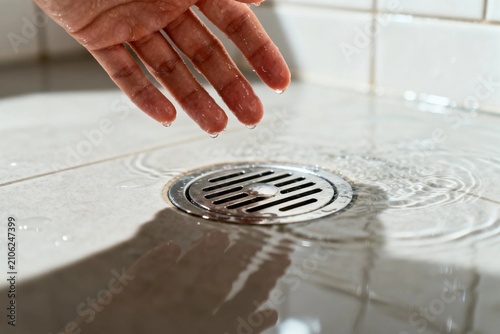 Hand Dropping Water into Shower Drain