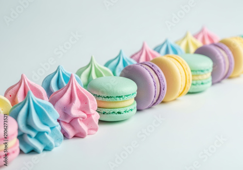Colorful pastel macarons and meringue cookies in a row